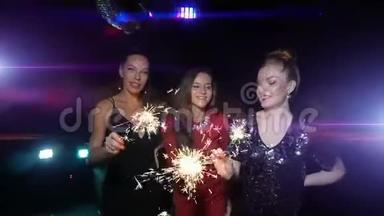 三个女人跳舞，玩得开心，在新年或<strong>圣诞</strong>晚会上捧起火花